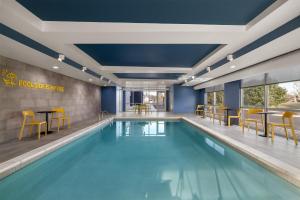 a swimming pool with chairs and tables in a building at Home2 Suites By Hilton Muncie in Muncie