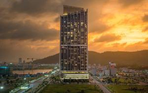 a tall building in front of a city at sunset at ICON40 Homestay Hạ Long - Ocean View in Ha Long