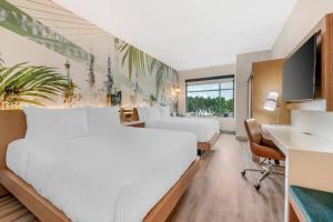 a hotel room with two beds and a desk at Cambria Hotel Tampa-Brandon in Tampa