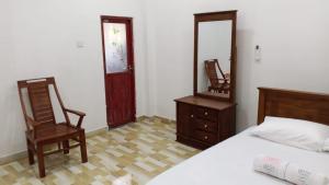 a bedroom with a bed and a mirror and a chair at Villa Rashel in Nikawatawana