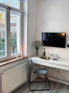 a white desk with a chair and a tv on a wall at Apartament 100m od morza in Sopot