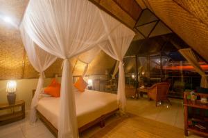 a bedroom with a bed with white drapes at Mbeliling Mountain Ecolodge in Noca