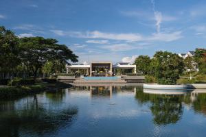 a house with a pond with two boats in it at Sunset Villa - Novaworld Phan Thiết in Bình Tú