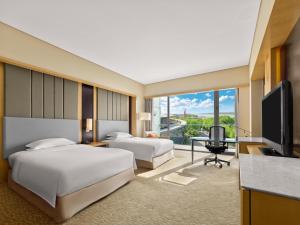 a hotel room with two beds and a flat screen tv at Hilton Nanjing Riverside in Nanjing +44 photos