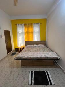 a bedroom with a bed and a yellow wall at Jorhat HideAway in Jorhat