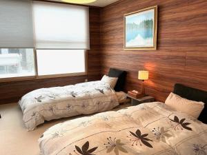 two beds in a room with wooden walls and windows at 猫と暮らす静かな一軒家 車1台駐車可 English Español available in Sapporo