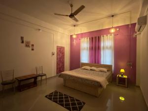 a bedroom with a bed and a pink wall at Jorhat HideAway in Jorhat