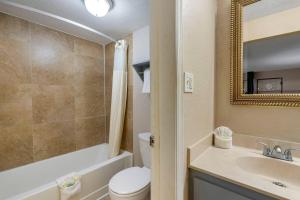 a bathroom with a toilet and a sink and a mirror at Rodeway Inn Clearwater-Dunedin in Clearwater +18 photos