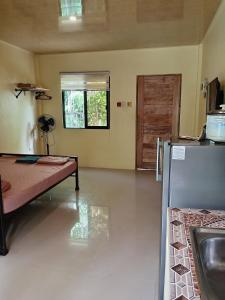 a room with a bed and a kitchen with a door at Bluewaves Apartment, scooter in Dauis