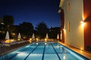 a swimming pool at night with chairs and tables at Frontemare Appartamenti e Camere ELISABETTA in Cesenatico
