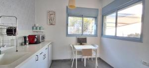 a white kitchen with a table and chairs in it at Nof Beresheet suites in Neot Golan +22 photos