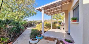 a porch of a white house with a pergola at Nof Beresheet suites in Neot Golan