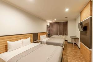 a hotel room with two beds and a television at Hwa Nan Hotel in Yongkang