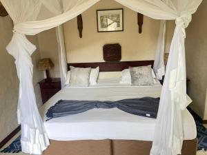 a bedroom with a canopy bed with white drapes at Inkindaba Guest Lodge in Victoria Falls +6 photos
