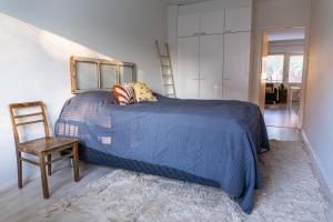a bedroom with a blue bed and a chair at Bright apartment in the Center in Kajaani