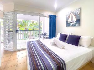 a bedroom with a large white bed and a balcony at Tropic Drift in Airlie Beach