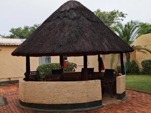 a gazebo with chairs and a straw roof at Inkindaba Guest Lodge in Victoria Falls