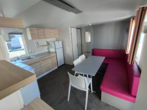 a small kitchen with a table and a red couch at Camping le Rochat Belle Isle in Châteauroux