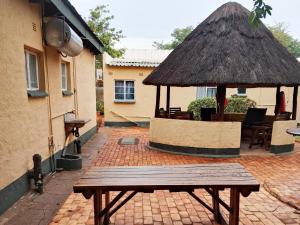 a pavilion with a wooden bench and a table at Inkindaba Guest Lodge in Victoria Falls