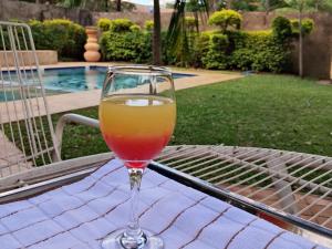 a glass of wine sitting on a table near a pool at Inkindaba Guest Lodge in Victoria Falls