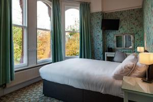 a hotel room with a large bed and windows at Sefton Park Hotel in Liverpool