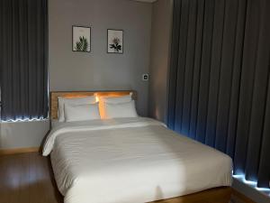 a bedroom with a large white bed with blue curtains at Sky Star in Incheon