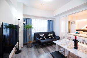 a living room with a couch and a table and a bed at Happy Osaka City in Osaka
