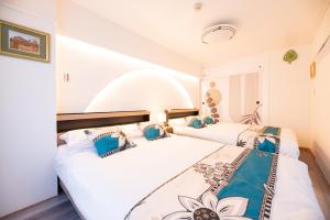 two beds in a room with white walls and blue pillows at Happy Osaka City in Osaka