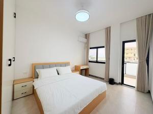 a bedroom with a white bed and a large window at Xiaos Henderson Hotel in Lungga