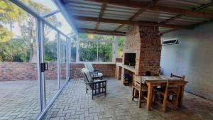 a patio with a brick fireplace and a table and chairs at Stay a While Self catering - Close to Greenacres Hospital, free Wi-Fi, and secure parking in Newton Park