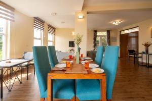 a dining room with a table and blue chairs at SaffronStays Valleyfall in Kotagiri