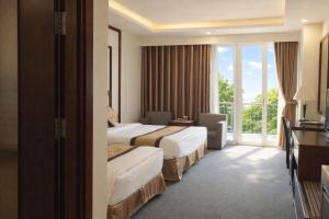 a hotel room with two beds and a balcony at Central Hotel in Móng Cái