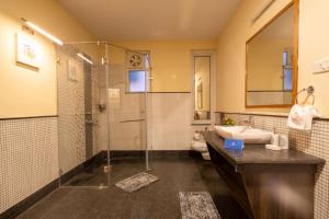 a bathroom with a glass shower and a sink at SaffronStays Valleyfall in Kotagiri +50 photos