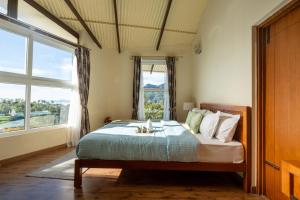 a bedroom with a bed and a large window at SaffronStays Valleyfall in Kotagiri