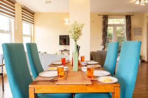 a wooden table with blue chairs and a dining room at SaffronStays Valleyfall in Kotagiri
