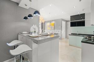 a kitchen with white cabinets and white stools at Nirasa by Kozystay - Paskal in Bandung