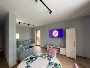 a living room with a table and a tv on a wall at Apartamenty Panoramic-Piecki in Piecki