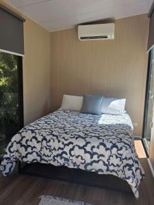 a bedroom with a bed with a blue and white comforter at Fassifern Tiny House 2 by Tiny Away in Lance Field