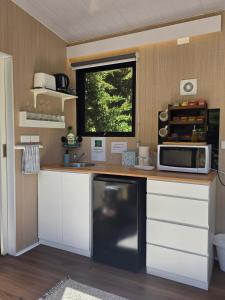 a kitchen with a counter with a microwave and a window at Fassifern Tiny House 2 by Tiny Away in Lance Field