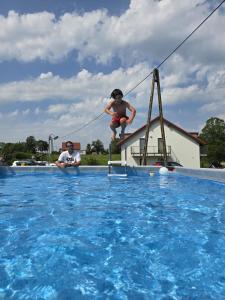 a boy jumping off a diving board in a swimming pool at Apartamenty Panoramic-Piecki in Piecki +14 photos