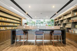 a library with two bar stools and bookshelves at Nirasa by Kozystay - Paskal in Bandung