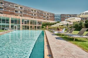 a swimming pool in front of a building at Falkensteiner Hotel & Spa Carinzia l 4 Star Superior in Tröpolach