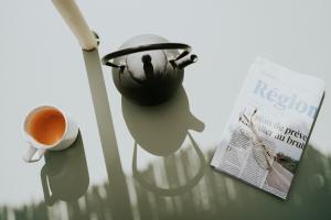 a tea pot and a newspaper next to a cup of coffee at Domaine La Commanderie in Boersch