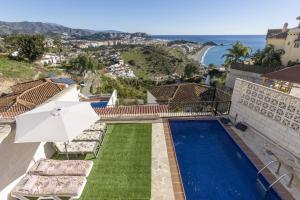 a house with a swimming pool and an umbrella at House Miramar almuñecar in Almuñécar