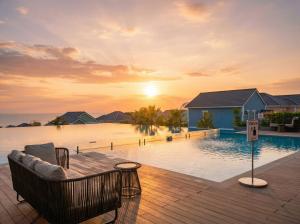 a resort pool with a couch and a sunset at Novaworld Phan Thiết - Alala Stay in Bình Sum