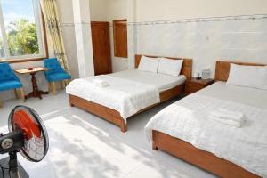 a bedroom with two beds and a fan in it at Sân Vườn Hotel Khánh Hòa in Ninh Hòa