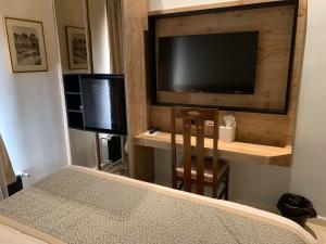 ein Schlafzimmer mit Bett und Flachbildfernseher in der Unterkunft El Boutique Hotel in Tyros