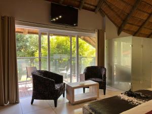a living room with two chairs and a tv on the wall at Highveld Splendour Boutique Bed and Breakfast in Ermelo