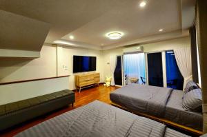 a bedroom with two beds and a flat screen tv at The Atlas hostel Muang Thong Thani in Thung Si Kan +12 photos