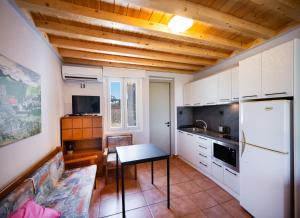 a kitchen with white cabinets and a table and a refrigerator at Santa Marina House in Lefkada